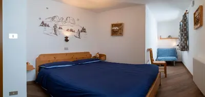 a bedroom with a blue bed and a chair at Casa Davarda - Appartamento Cima Dodici in Vigo di Fassa