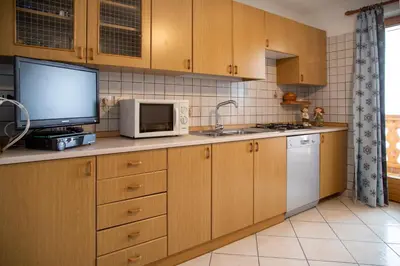 a kitchen with wooden cabinets and a microwave and a tv at Casa Davarda - Appartamento Cima Dodici in Vigo di Fassa