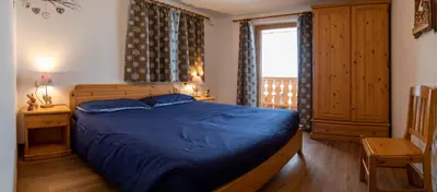 a bedroom with a blue bed and a window at Casa Davarda - Appartamento Cima Dodici in Vigo di Fassa