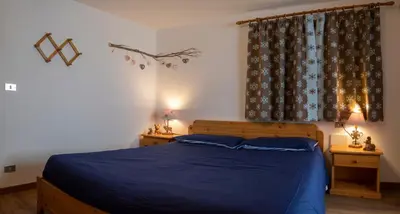 a bedroom with a bed with blue sheets and a window at Casa Davarda - Appartamento Cima Dodici in Vigo di Fassa