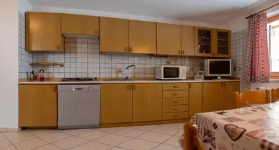 a kitchen with wooden cabinets and a white dishwasher at Casa Davarda - Appartamento Lusia in Vigo di Fassa