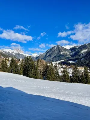 a snow covered field with mountains in the background at Casa Davarda - Appartamento Lusia in Vigo di Fassa