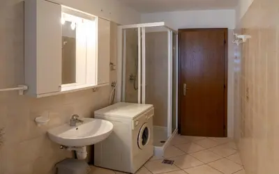 a bathroom with a sink and a washing machine at Casa Davarda - Appartamento Lusia in Vigo di Fassa