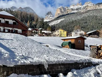 a village covered in snow with mountains in the background at Casa Davarda - Appartamento Lusia in Vigo di Fassa