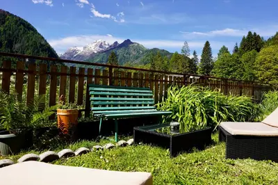 a green bench sitting in a yard with mountains in the background at Casa vacanze Danoi Dolomiti in Canale dʼAgordo