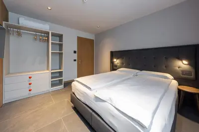 a bedroom with a large white bed and a table at Dolomiten Apartments in Tesero