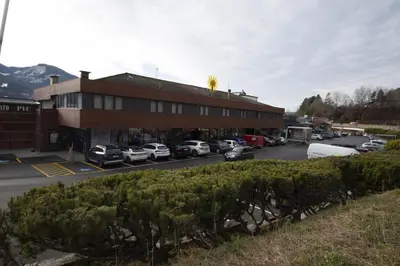a building with cars parked in a parking lot at Dolomiten Apartments in Tesero