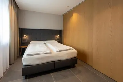 a bedroom with a large bed with a wooden wall at Dolomiten Apartments in Tesero