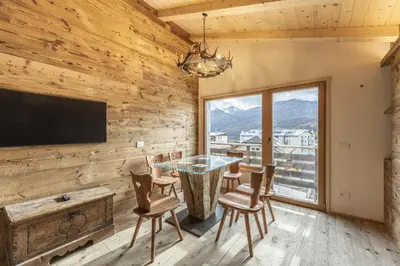 a dining room with a table and chairs and a large window at Casa Poligrafica 1 in Cortina dʼAmpezzo