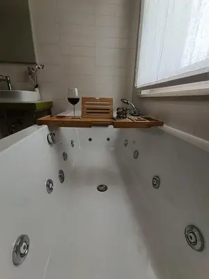 a bathroom with a bath tub with a glass of wine at Casa Evelina con Parcheggio esterno e Garage gratis, appartamento con idromassaggio per due in Sanzeno