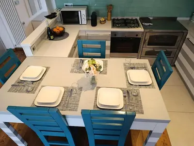 a kitchen with a table with blue chairs and a counter at Casa Evelina con Parcheggio esterno e Garage gratis, appartamento con idromassaggio per due in Sanzeno