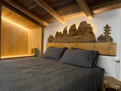 a bedroom with a bed with a wooden headboard at SciaLet in Campitello di Fassa