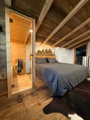a bedroom with a bed in a room with wooden floors at SciaLet in Campitello di Fassa