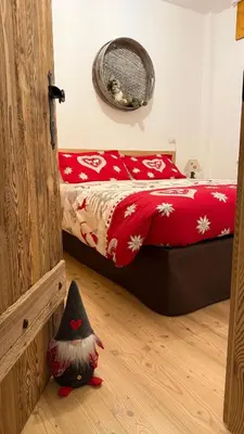a bedroom with a bed with red sheets and a toy at SciaLet in Campitello di Fassa