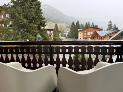 two white chairs on a balcony with a view at SciaLet in Campitello di Fassa