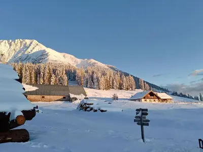 a snow covered field with a house in the background at Luigi Apartment in Varena