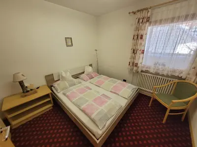a bedroom with a bed and a chair and a window at Chalet Milandora in La Villa