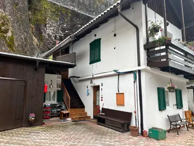 a white building with green shuttered windows and a staircase at Casa Angela in Cavalese