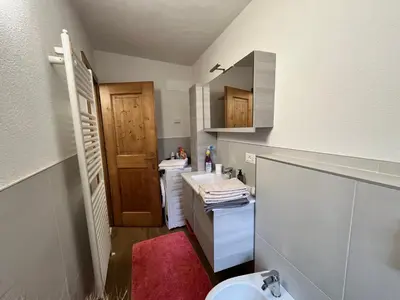 a small bathroom with two sinks and a toilet at Casa Angela in Cavalese