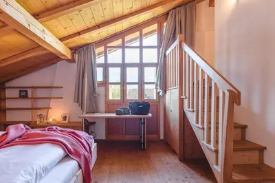 a bedroom with a bed and a staircase with a window at Maso Via Vecchia in Ora/Auer
