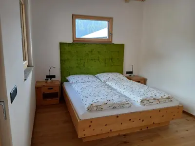 a bedroom with a bed with a green headboard and a window at Reitererhof in Hafling