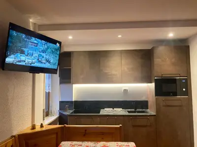 a kitchen with a flat screen tv on the wall at Appartamento Casa Latemar in Predazzo