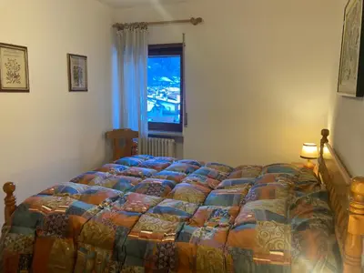 a large bed in a bedroom with a window at Appartamento Casa Latemar in Predazzo
