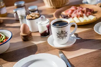 a table with a cup of coffee and a plate of food at Großplonerhof in Luson