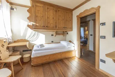 a bedroom with a bed and a wooden cabinet at Casa Maddalena, quiet and very comfortable in Cortina dʼAmpezzo