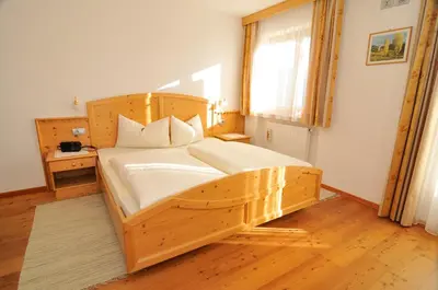 a bedroom with a wooden bed in a room at Prantschurhof in San Pietro in Gardena