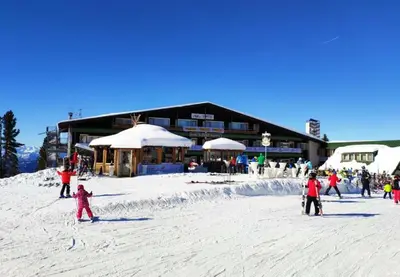 a group of people standing in the snow in front of a ski lodge at Eurotel Cermis in Cavalese