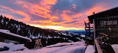 a sunset in the mountains with snow and a building at Eurotel Cermis in Cavalese