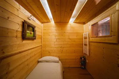 a small room with a bed in a wooden cabin at Dolomiti Urban Lodge - casa Civetta in Cencenighe