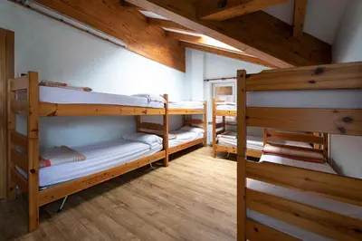 three bunk beds in a room with wooden ceilings at Rifugio Cereda - Dormitory in San Martino di Castrozza