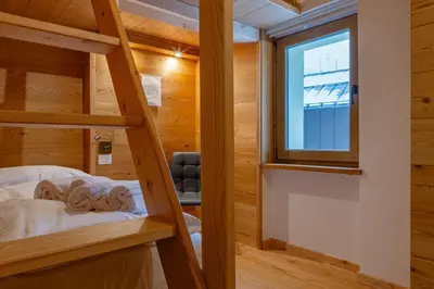 a bedroom with a large white bed with wooden ceilings at Appartamenti Dolomites Elements in Caprile