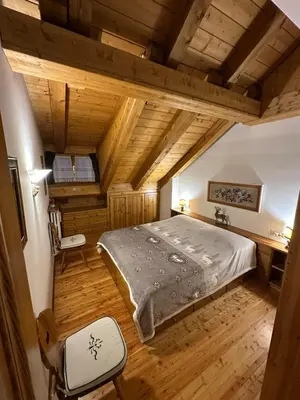 a bedroom with a large bed and a wooden floor at Mansarda Ca' Fiori city center San Vito di Cadore in San Vito di Cadore