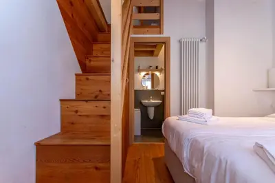 a bedroom with a bed and a bathroom with a sink at Wonderful appartment Monte Civetta in Dolomites in Alleghe