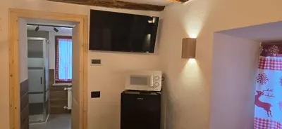 a room with a refrigerator and a table and chairs at Rifugio Kristine in Falcade
