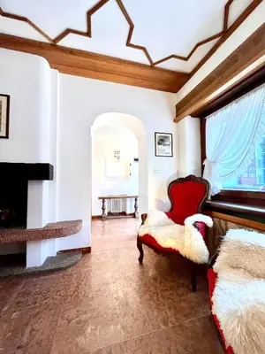 a living room with a fireplace and a red chair at Cortina Relax in Cortina dʼAmpezzo