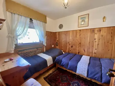a bedroom with two beds and a window at Charming ground floor flat with mountain views in Cortina dʼAmpezzo