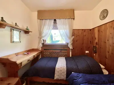 a bedroom with a bed and a desk and a window at Charming ground floor flat with mountain views in Cortina dʼAmpezzo