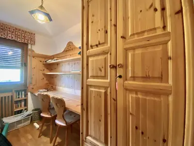 a room with a desk and a closet with wooden cabinets at Charming ground floor flat with mountain views in Cortina dʼAmpezzo