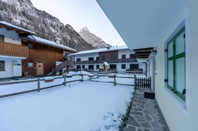 a snow covered yard with buildings and mountains in the background at Cesa Vivi in Canazei