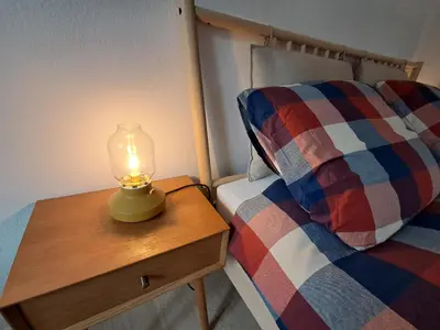 a lamp on a wooden table next to a bed at La Casa di Elvira-Primo Piano in Alleghe