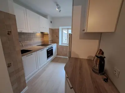 a kitchen with white cabinets and a wooden floor at La Casa di Elvira-Primo Piano in Alleghe
