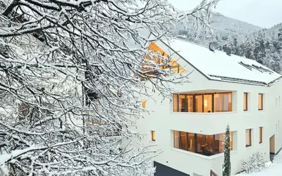 a building covered in snow with snow covered trees at Kreithner luxury apartments in Vandoies