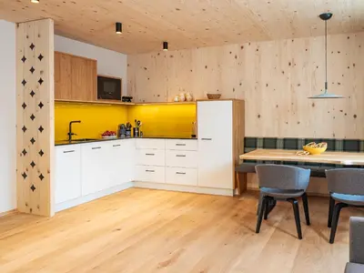 a kitchen with white cabinets and a table with chairs at Kreithner luxury apartments in Vandoies