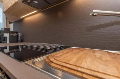 a stove top with a wooden cutting board on it at Alpine Nest in Rocca Pietore