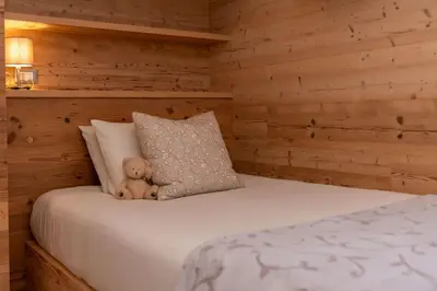 a teddy bear sitting on top of a bed at Alpine Nest in Rocca Pietore