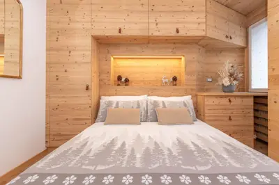a bedroom with a bed with a wooden wall at Alpine Nest in Rocca Pietore